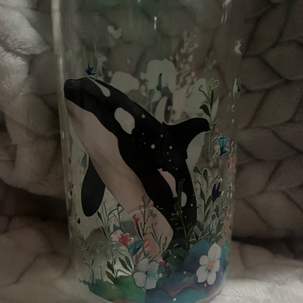 A 16 ounce dolphin themed glass tumbler with acrylic lid and glass straw